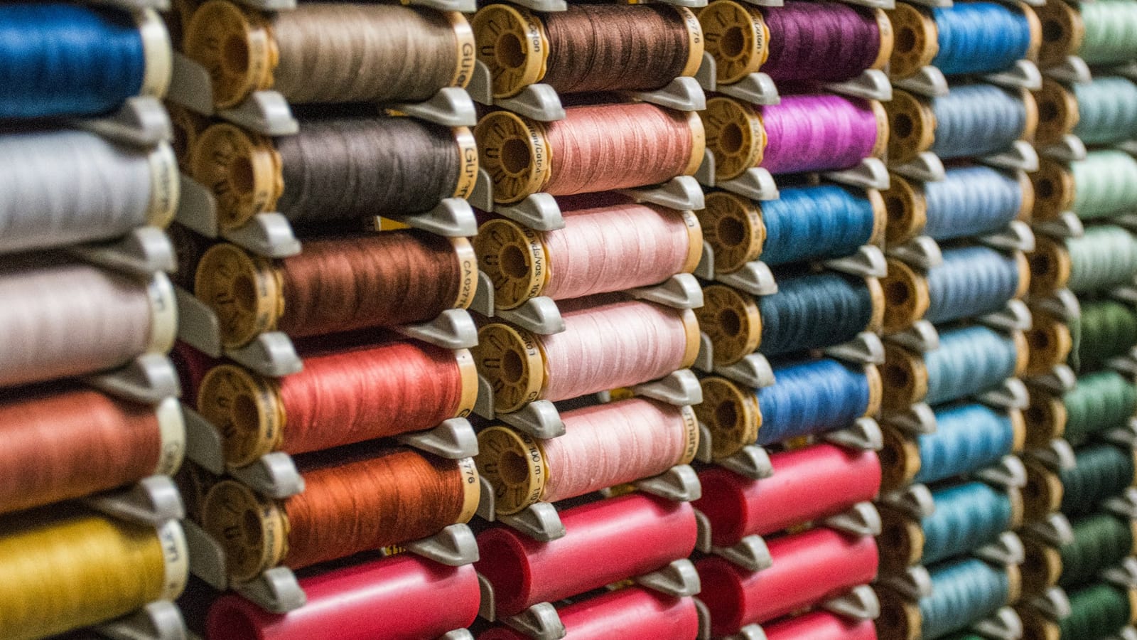 Rows of colourful thread spools on a textile machine